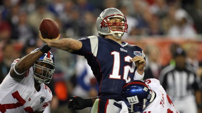 New England Patriots quarterback Tom Brady (C) passes the ball despite Osi Umenyiora (L) and Justin Tuck