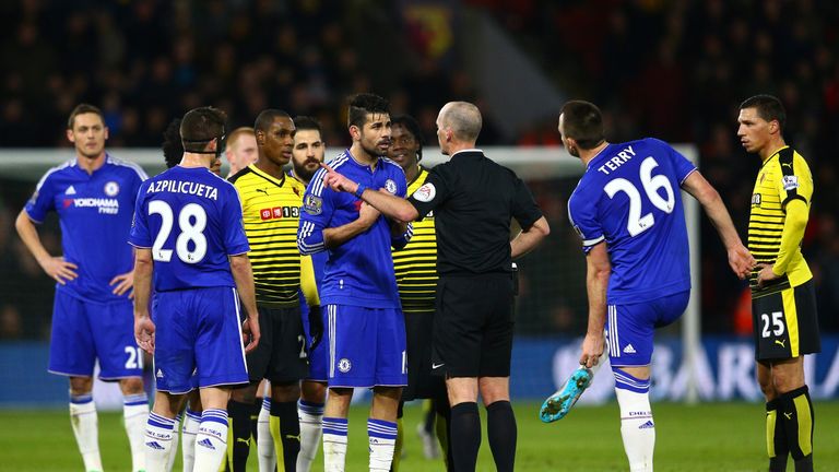Referee Mike Dean prepares to show the yellow card to Diego Costa
