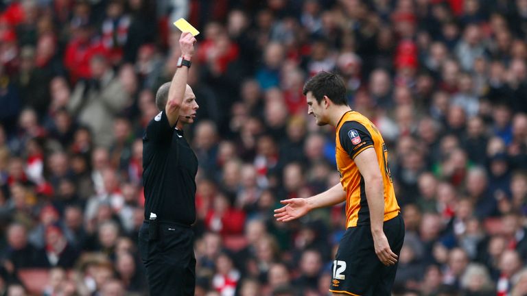 Harry Maguire of Hull City is shown a yellow card by referee Mike Dean during the Emirates FA Cup fifth round match against Arsenal