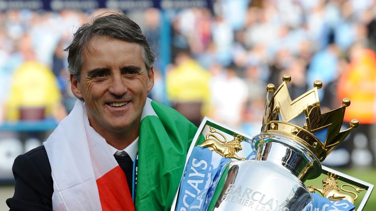 Manchester City's Italian manager Roberto Mancini celebrates with the Premier League trophy after their 3-2 victory over Queens Park Rangers in May 2012