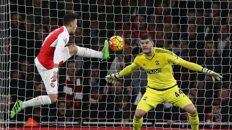 Arsenal's Mesut Ozil (L) leaps in an effort on goal as Southampton's Fraser Forster (R) defends