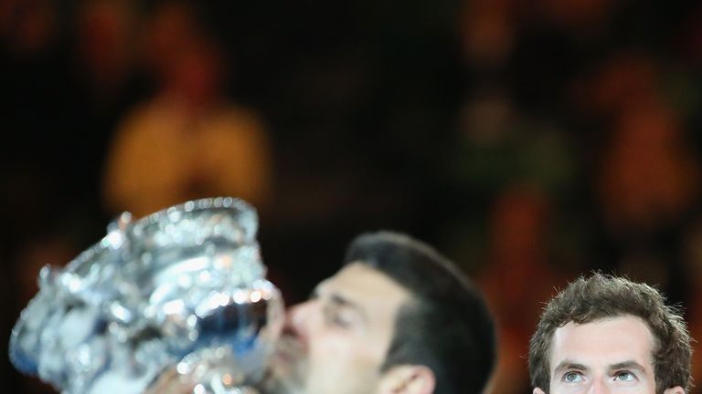 Andy Murray of Great Britain looks on as Novak Djokovic of Serbia holds the trophy