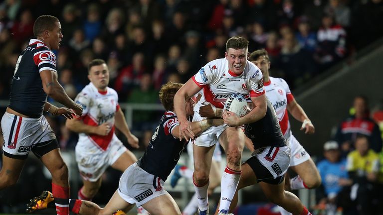 Joe Greenwood of St Helens is tackled by Dylan Napa and Sio Siua Taukeiaho of Sydney Roosters during the World Club Series match