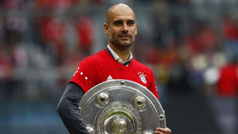 Bayern Munich's coach Pep Guardiola holds the Bundesliga trophy.