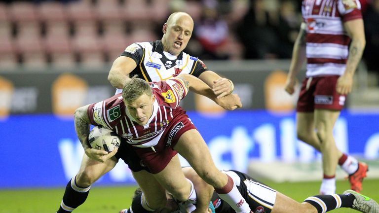 Wigan wing Dom Manfredi is tackled by Salford's Michael Dobson and Tommy Lee