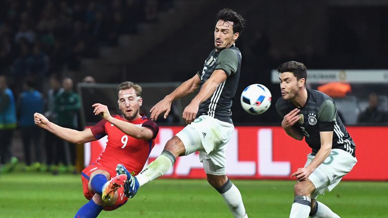 Harry Kane (L) of England shoots at goal while Mats Hummels (C) and Jonas Hector (R) of Germany try to block 