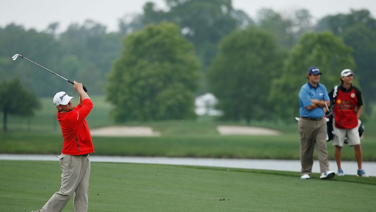 J.B. Holmes hits his second shot of the second playoff hole, as Johnson Wagner and his caddie look on, at the Shell Houston Open 