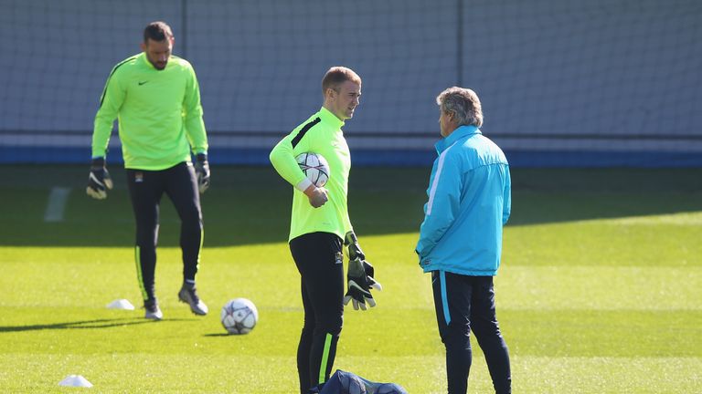 Joe Hart of Manchester City talks to manager Manuel Pellegrini during a training session ahead of the UEFA Champions League