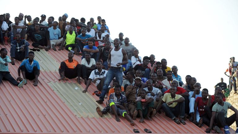 Supporters sit on the roof of a house to watch the African Cup of Nations qualification match between Egypt and Nigeria