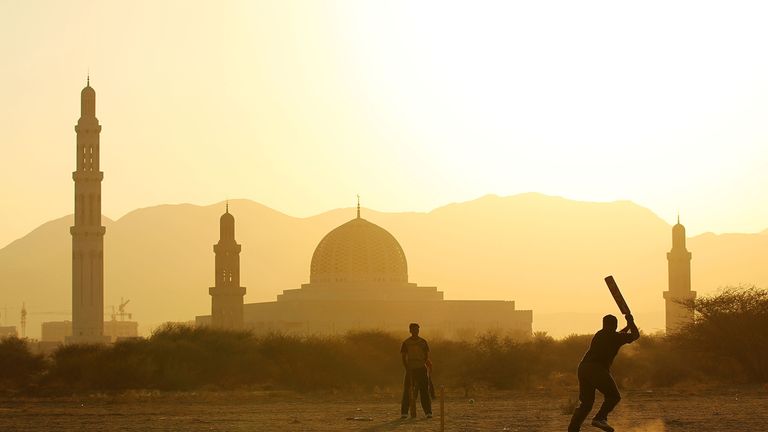 Locals play cricket behind the Sultan Qaboos Grand Mosque in Muscat, Oman