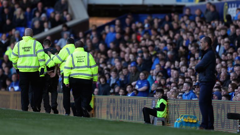 Everton support team carry off a pitch invaider during the Barclays Premier League match between Everton and Southampton at