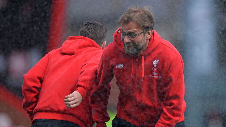 Liverpool manager Jurgen Klopp (right) and Reds midfielder Adam Lallana react as a sprinkler catches the pair