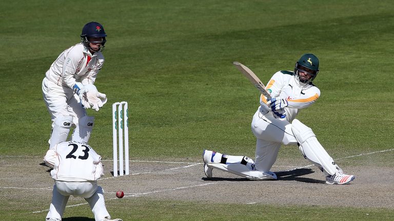 Michael Lumb of Nottinghamshire sweeps with Alex Davies of Lancashire looking on as Haseeb Hameed takes cover