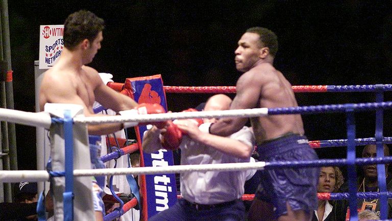 Mike Tyson (R) goes through and over the referee (C) to get at Lou Savarese during the first round of their scheduled 10-round bout at Hampden Park in Glas