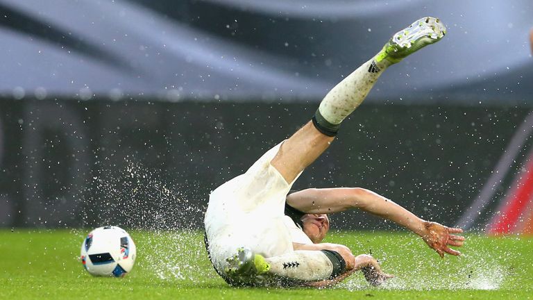 Germany's Julian Draxler slides on the rain-sodden turf in Augsburg