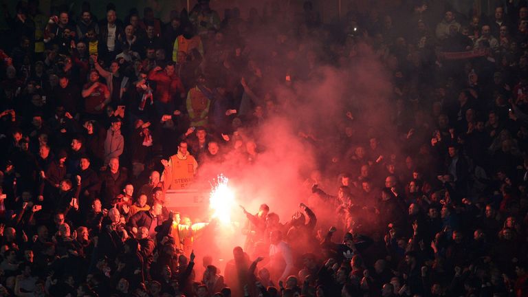 A flare is lit during the match between Manchester United and Liverpool