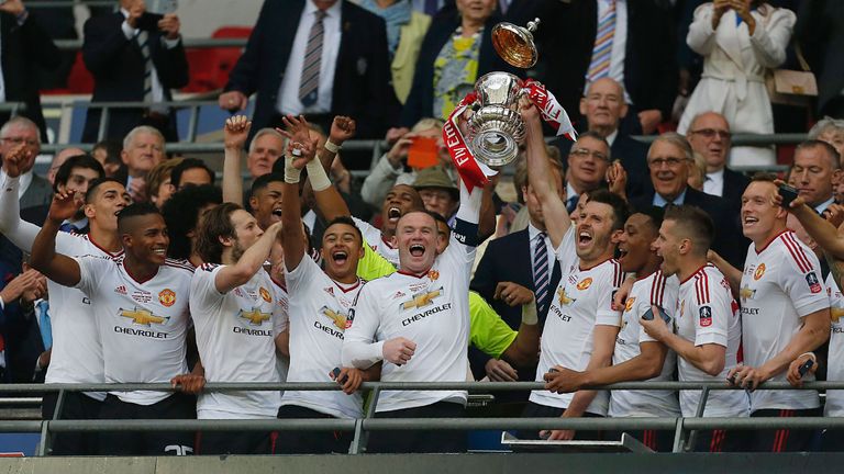 Manchester United's English striker Wayne Rooney (centre left) and Manchester United's English midfielder Michael Carrick lift the trophy