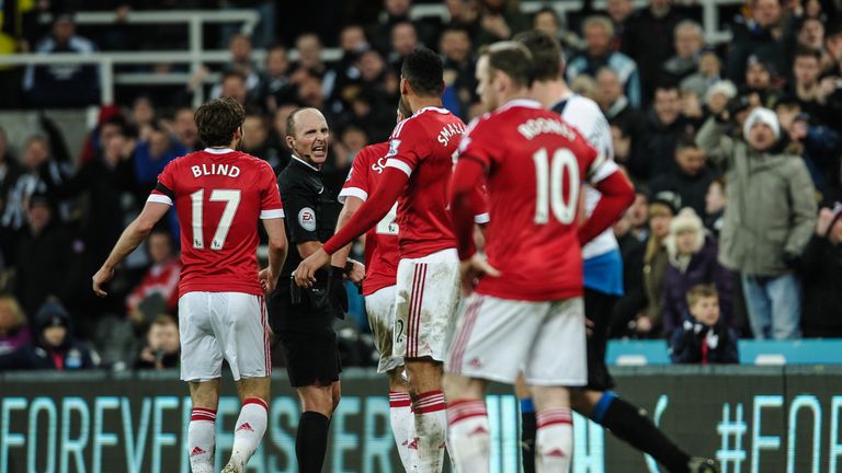 NEWCASTLE, ENGLAND - JANUARY 12:  Referee Mike Dean (second from left) reacts as Manchester player surround him  during the Barclays Premier League match b