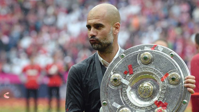 Pep Guardiola holds the trophy as he and the team celebrate their Bundesliga title.