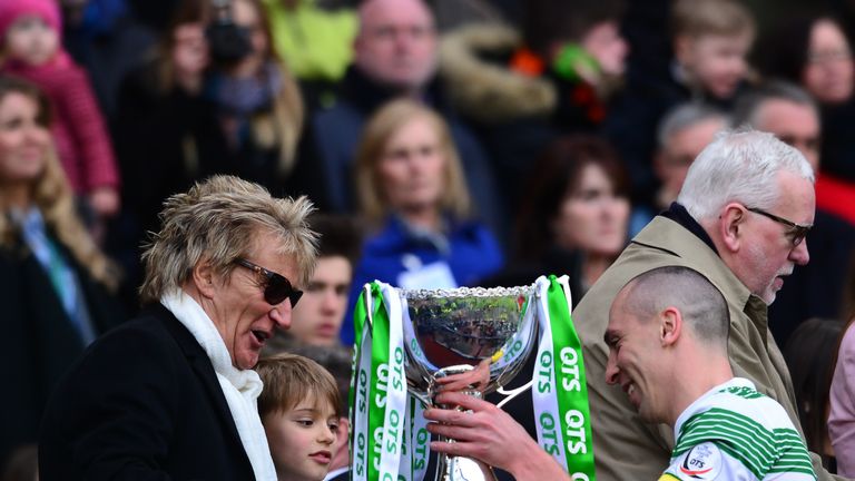 Celtic captain Scott Brown is presented with the League Cup trophy by life long Celtic fan Rod Stewart (L), as the Celtic te