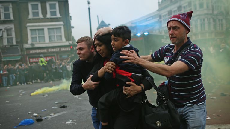 A woman and a child are shielded by fans as violence erupts