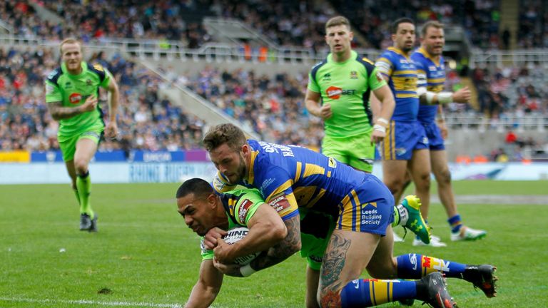 Isa scores a try for Wigan as he holds off Leeds' Zak Hardaker 