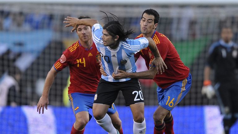 Argentina's midfielder Ever Banega (C) vies for the ball with Spain's midfielder Sergio Busquets (R) and midfielder Xabi Alonso during a friendly