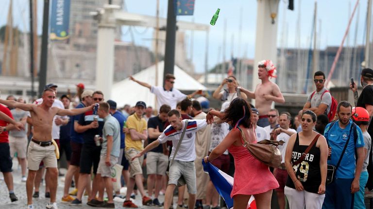 A French woman (in pink) throws a beer bottle towards English football fans as they gather in the old town area of Marseille ahead of the first game in Euro 2016.