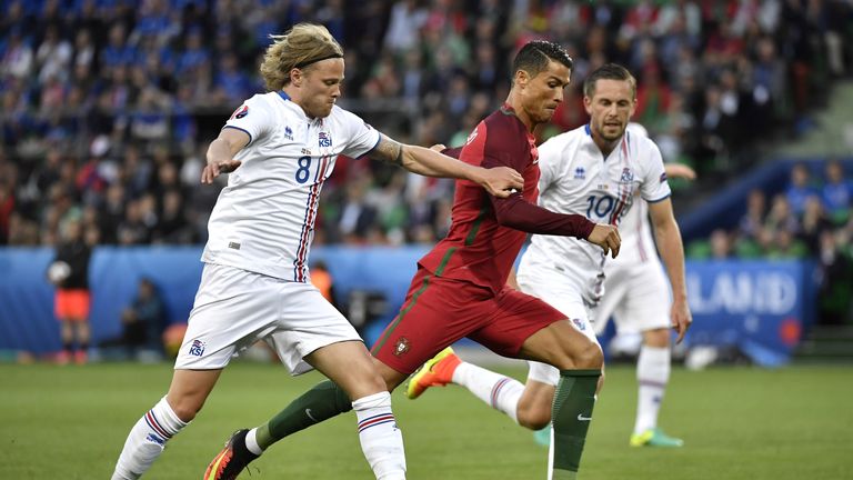 Iceland's midfielder Birkir Bjarnason (L) and teammate Iceland's midfielder Gylfi Sigurdsson vies for the ball against Portugal's forward Cristiano Ronaldo