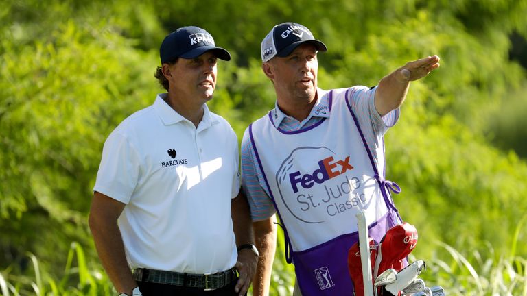 Phil Mickelson and caddie Jim Mackay speak as he prepares to hit off the 12th tee during the first round of the FedEx St. Jude Clas