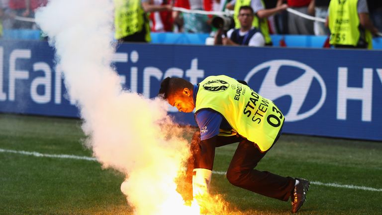 A steward picks up a flare which was thrown onto the pitch by supporters during the UEFA Euro 2016 Group F match between Iceland and Hungary