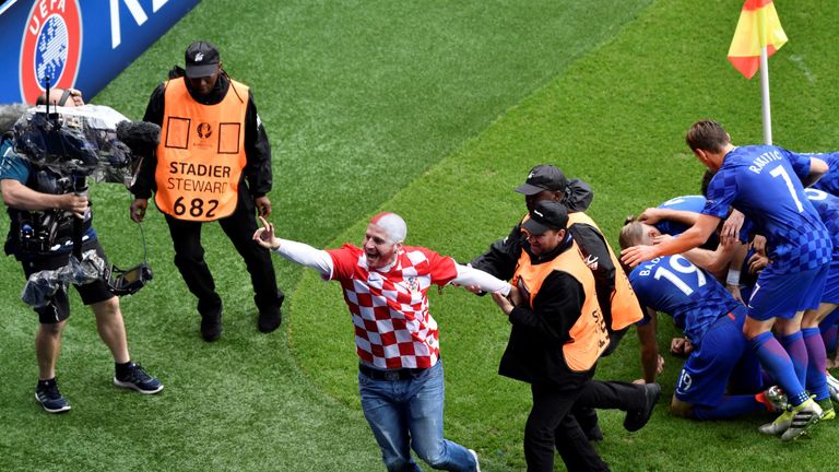 Security escort a fan off the pitch as he tried to celebrate with Croatia's midfielder Luka Modric