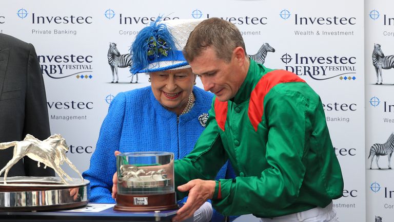 Queen Elizabeth II presents the trophy to jockey Pat Smullen after Harzand wins the Investec Derby