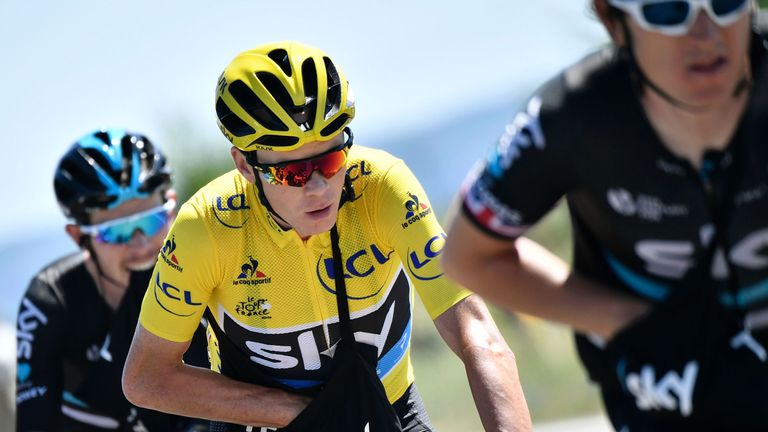 Great Britain's Christopher Froome (C), wearing the overall leader's yellow jersey, searches in his feed bag as he rides with his teammates in the pack, du