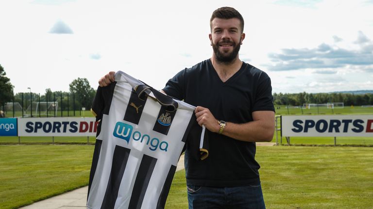 Grant Hanley poses for photographs holding a home shirt at the Newcastle United Training Centre