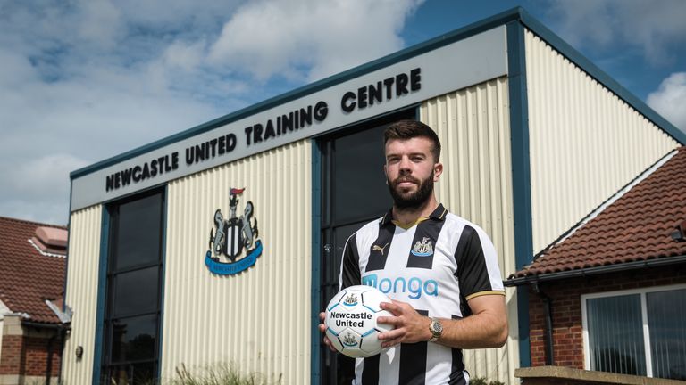 Grant Hanley poses for a photograph wearing a home shirt and holding a football at the Newcastle United Training Centre