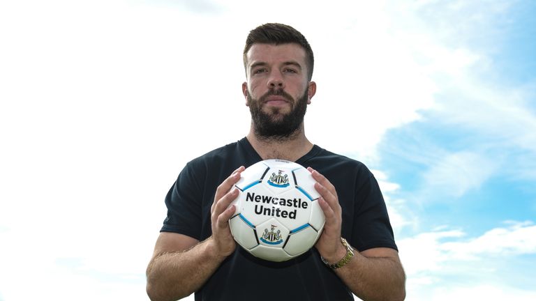 Grant Hanley poses for photographs holding a football at the Newcastle United Training Centre
