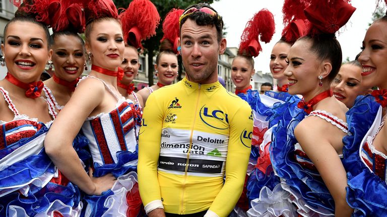 Great Britain's Mark Cavendish, wearing the overall leader's yellow jersey,  poses with French can-can dancers prior to the start of the 183 km second stag