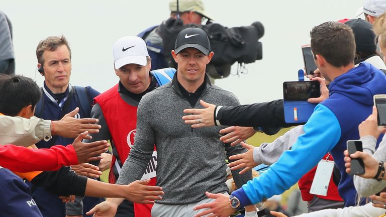 McIlroy taps hands with spectators as he walks between holes during the final round