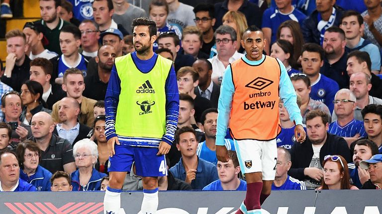 Cesc Fabregas of Chelsea looks on from the sidelines with Dimitri Payet of West Ham United 