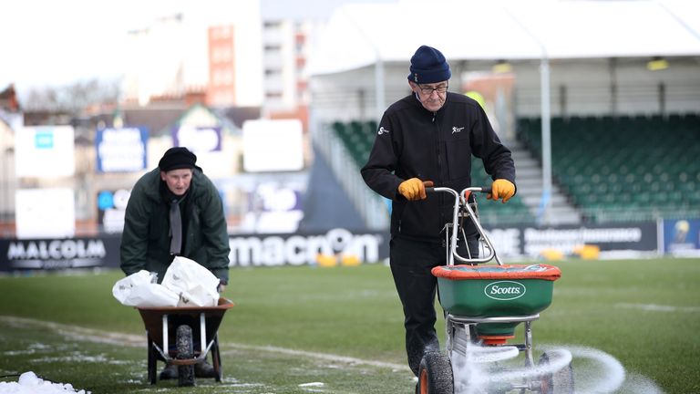 Groundsmen spread salt around the edge of the pitch ahead of the European Rugby Champions Cup rugby union match between Glasgow and Montpellier at Scotstou