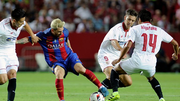 Lionel Messi (C) vies for the ball with Hiroshi Kiyotake (R) during the Spanish Super Cup first leg match between Sevilla and Barcelona