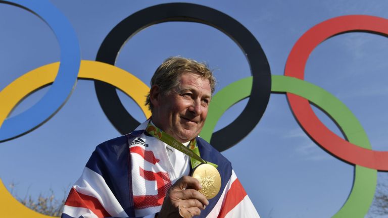 Britain's Nick Skelton celebrates with his gold medal in front of the Olympic rings after the individual equestrian show jumping event during the Rio 2016 
