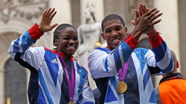 British Olympic boxing gold medalists Nicola Adams and Anthony Joshua (R) wave to the crowd as as they go past St Paul's