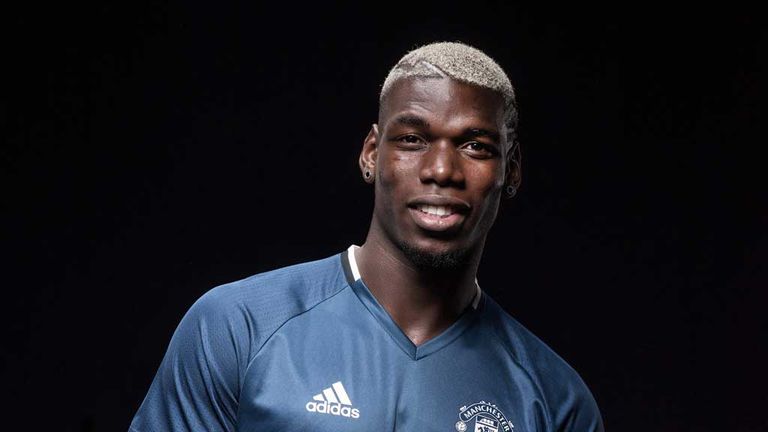 Paul Pogba points to the Manchester United badge - and smiles