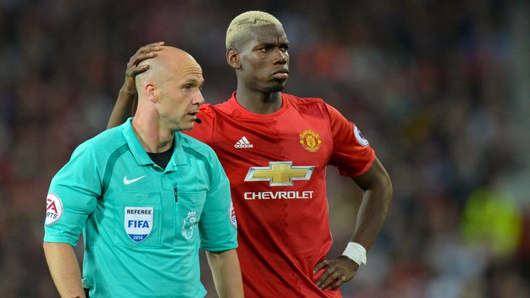 Paul Pogba (R) shares a moment with referee Anthony Taylor