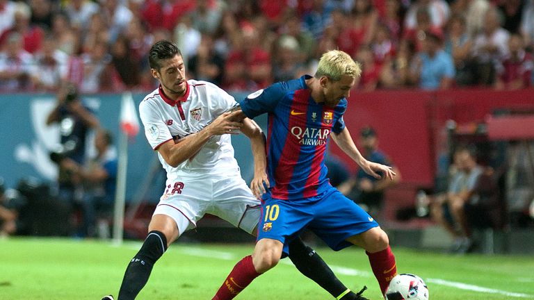 Sergio Escudero (L) vies for the ball with Lionel Messi during the first leg of the Spanish Super Cup match between Sevilla and Barcelona