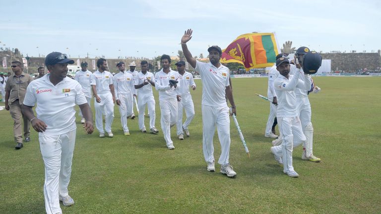 Sri Lankan cricketers Rangana Herath, (L), Dilruwan Perera (C) and team members acknowledge the crowd as they celebrate their victory in the second Test ma