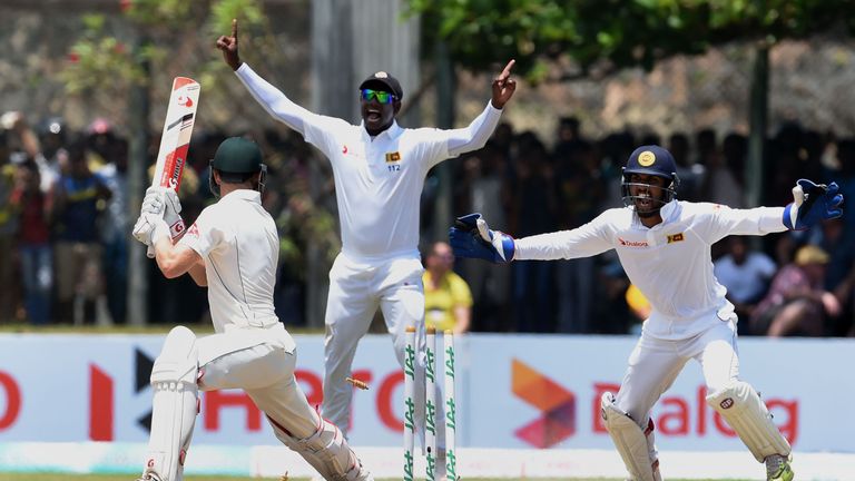 Bails fly as Sri Lanka's captain Angelo Mathews (C) and wicketkeeper Dinesh Chandimal (R) celebrate the wicket of Australian cricketer Adam Voges (L) durin