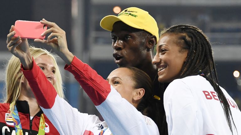 Jamaica's Usain Bolt poses for pictures with track and field athletes after he won the Men's 100m Final during the athletics event at the Rio 2016 Olympic 